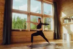 Frau macht Yoga in einem Holzraum mit Fenstern