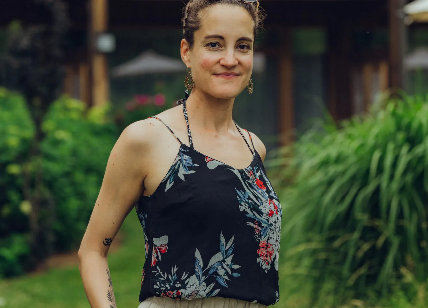 Lächelnde Person in einem Blumenshirt im Garten.